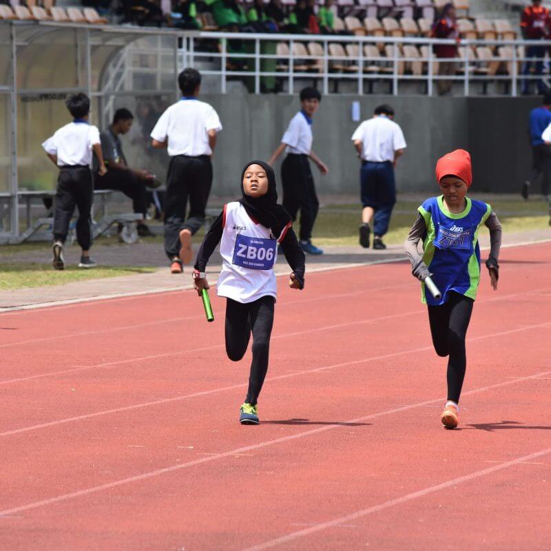 Zwei Mädchen mit Kopftuch beim Staffellauf