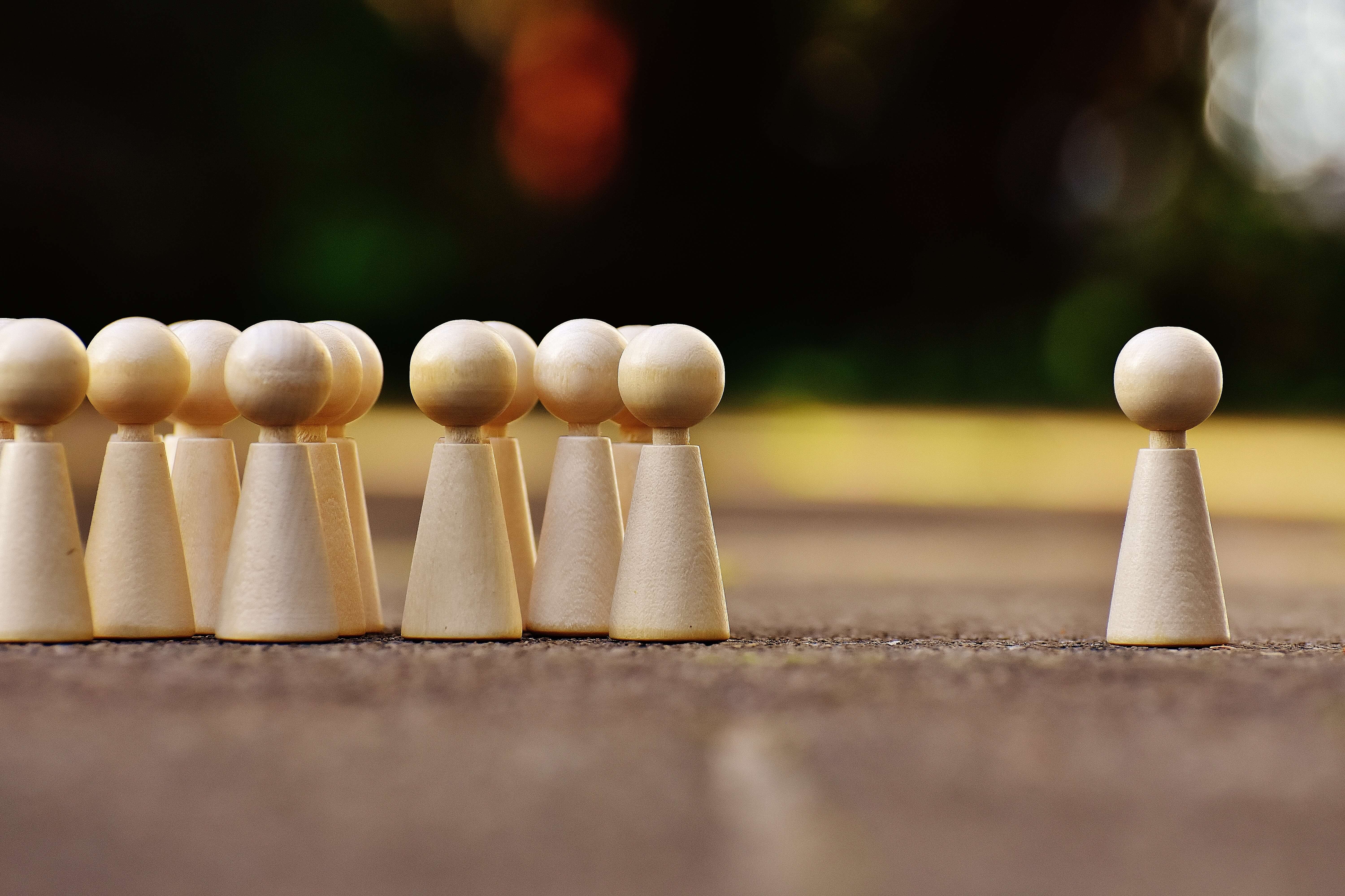 Spielfiguren als Gruppe stehen neben einer einzelnen Spielfigur