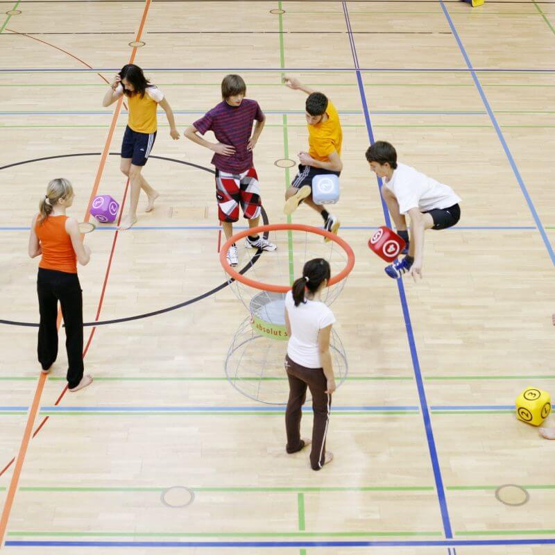 Eine Gruppe von Kindern spielt Fußball mit Würfeln in einer Turnhalle