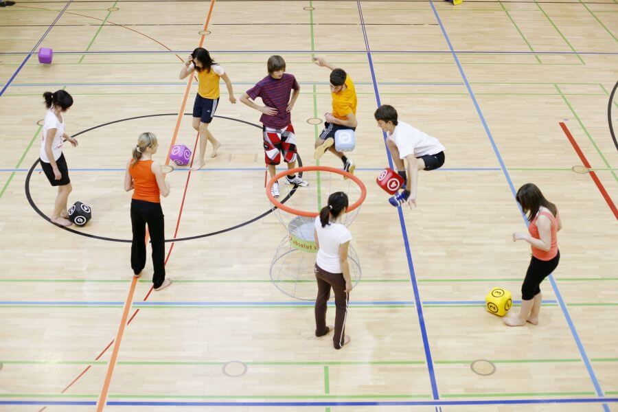 Eine Gruppe von Kindern spielt Fußball mit Würfeln in einer Turnhalle