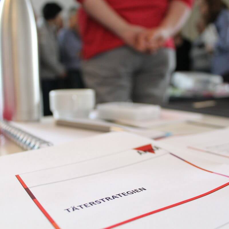 Auf einem Tisch liegt ein Zettel mit der Aufschrift Täterstrategien