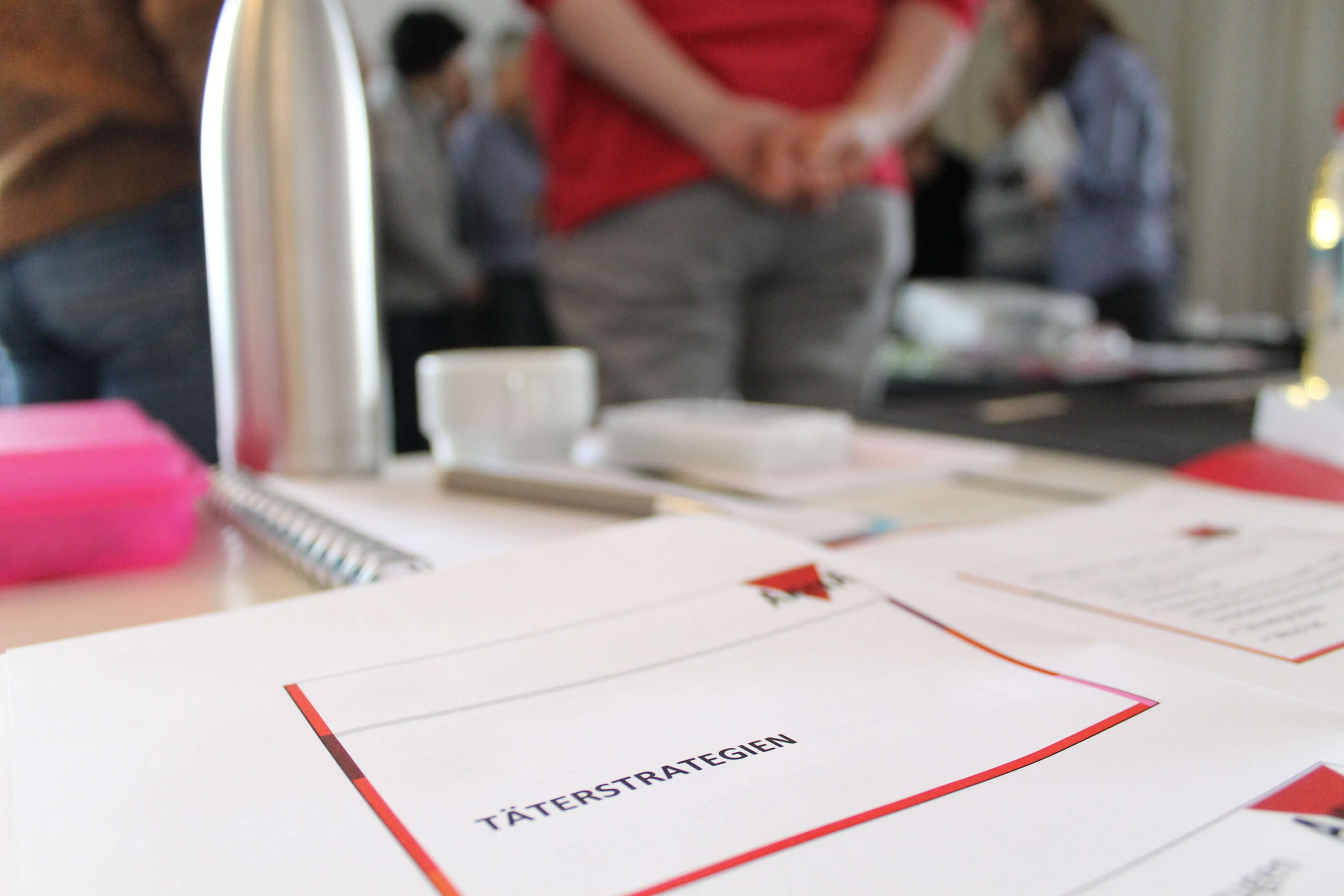 Auf einem Tisch liegt ein Zettel mit der Aufschrift Täterstrategien