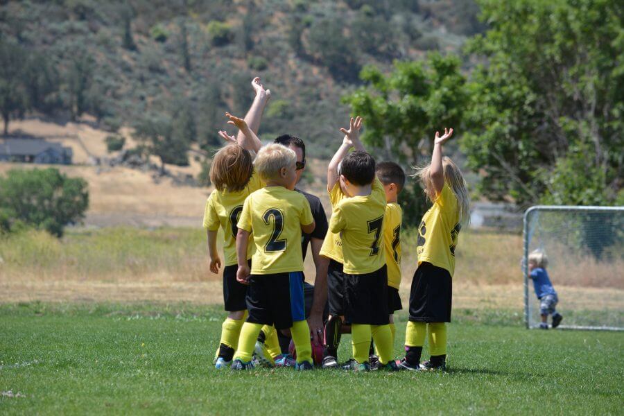 Kleine Kinder auf dem Fußballplatz klatschen ab