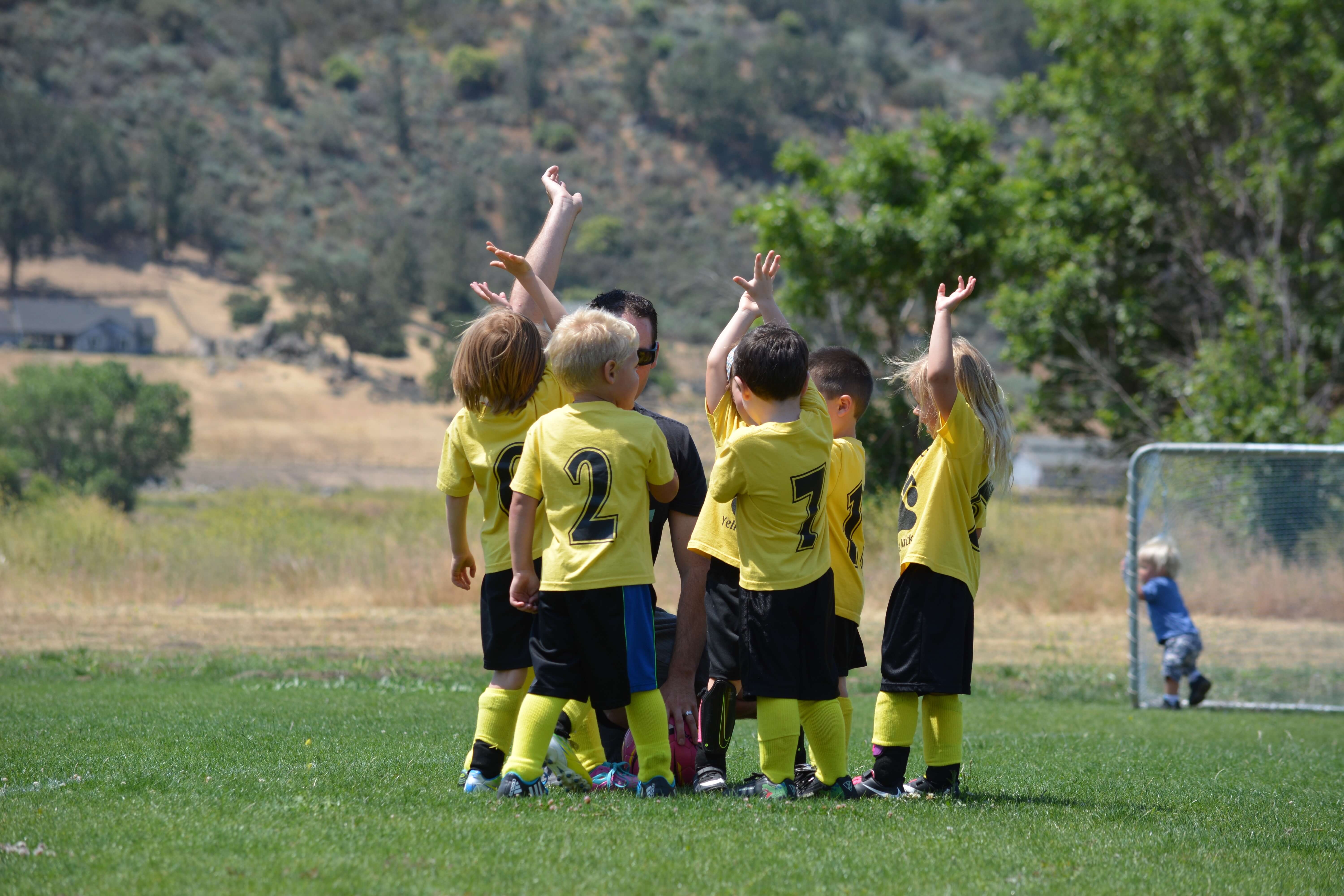 Kleine Kinder auf dem Fußballplatz klatschen ab