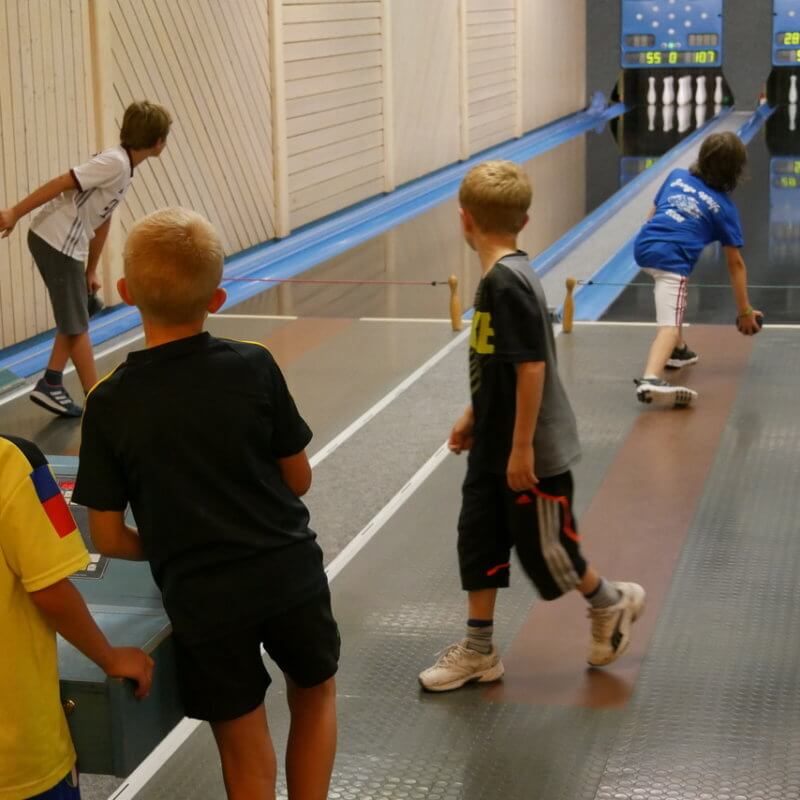 fünf Kinder auf einer Kegelbahn