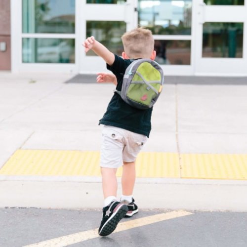 Ein Junge läuft freudig auf ein Gebäude zu