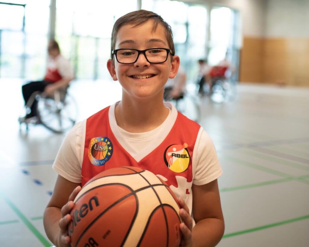 Ein Junge hält einen Basketball vor der Brust