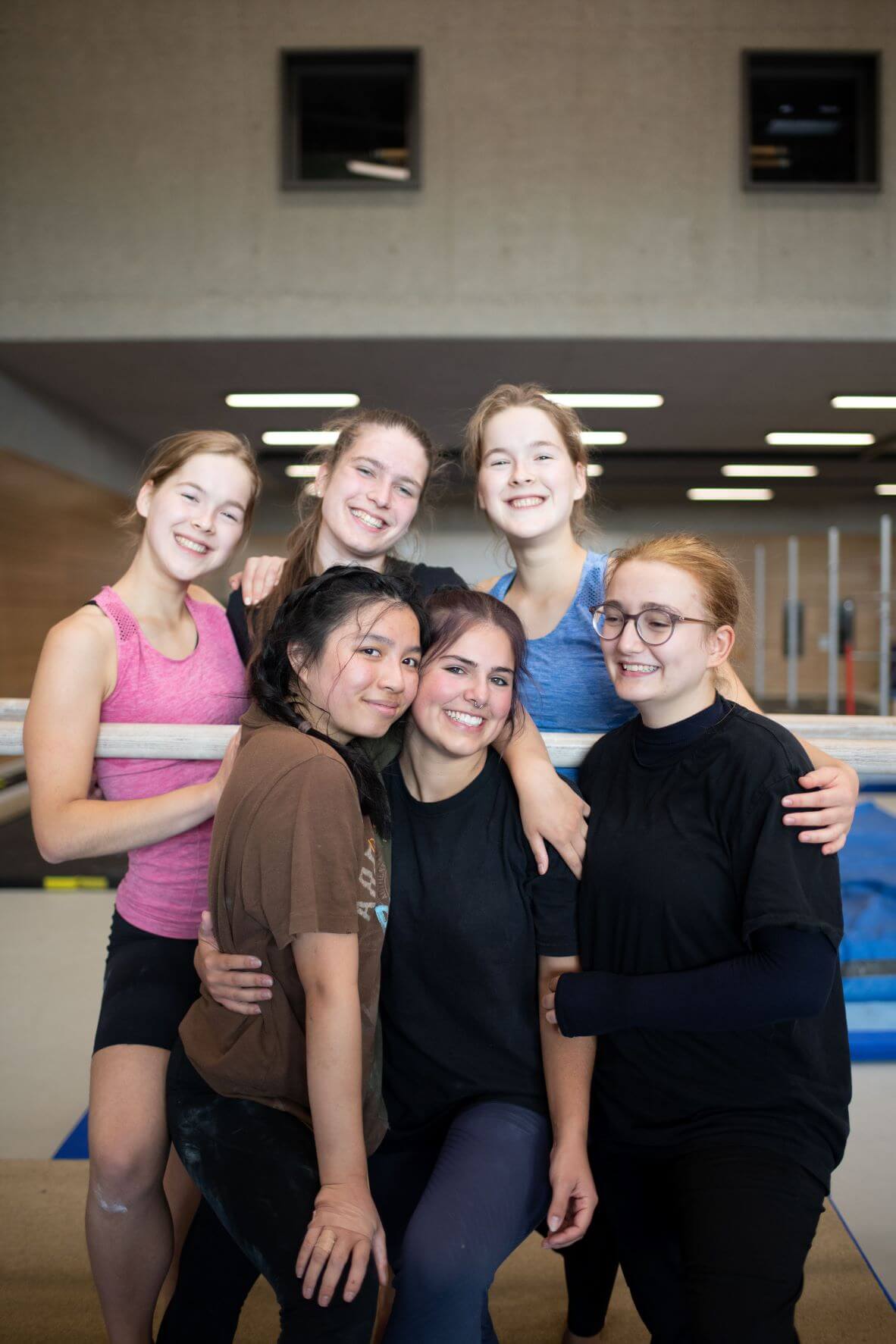 Sechs Mädchen stehen in einer Turnhalle und umarmen sich