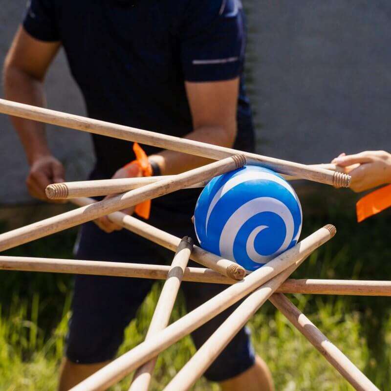 Viele Besenstiele halten einen blau-weißen Ball in der Luft