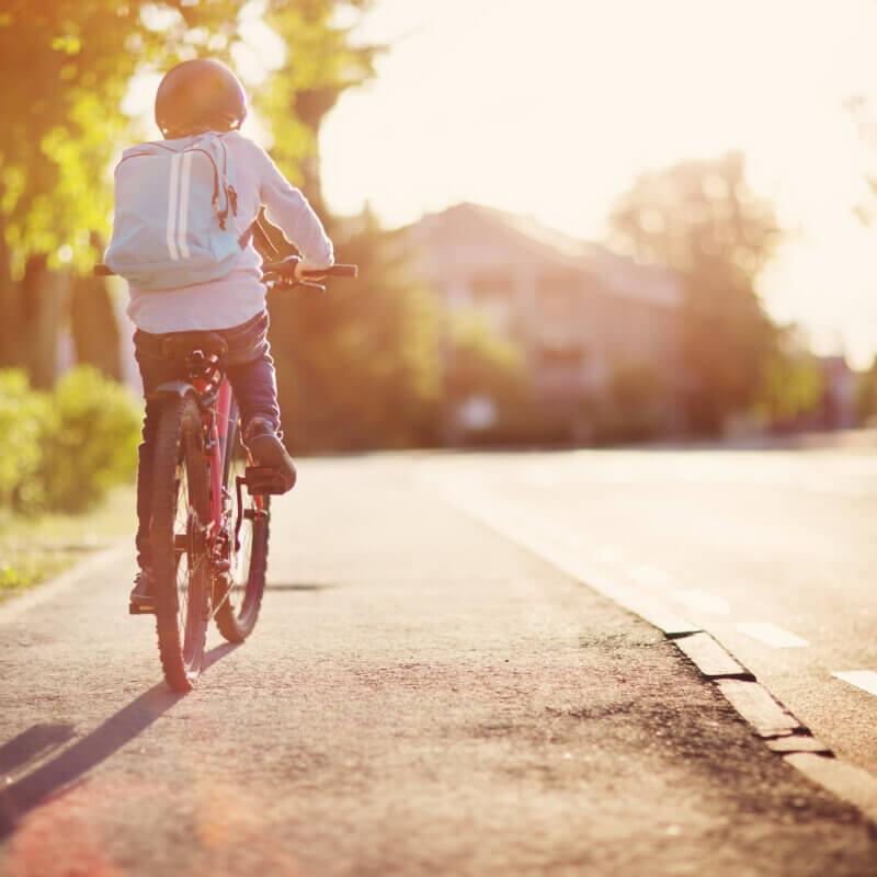 Kind mit Rucksack fährt Fahrrad