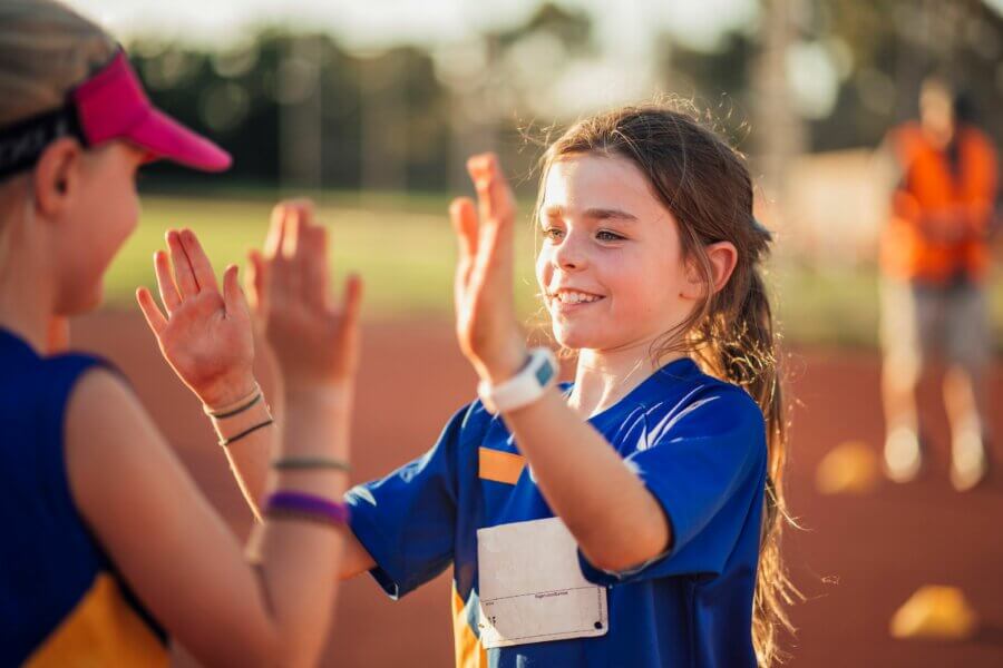 Zwei Mädchen auf einem Sportplatz klatchen ab