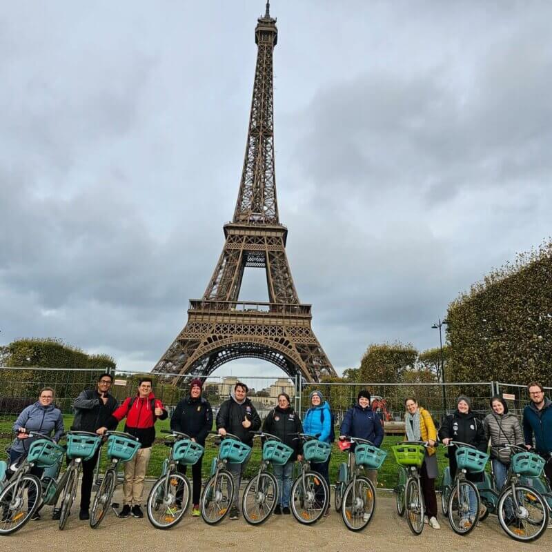Eine Gruppe von Menschen auf Fahrrädern. Im Hintergrund der Eifelturm