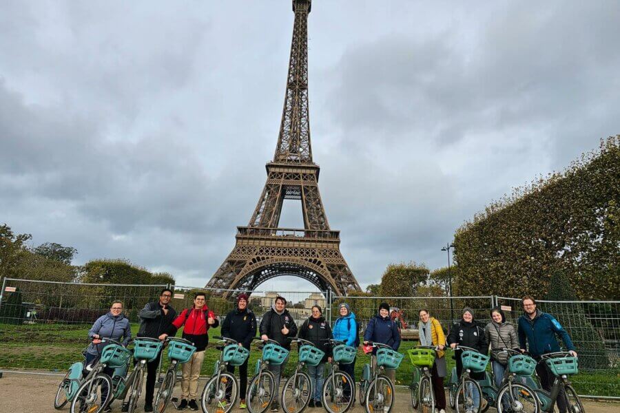 Eine Gruppe von Menschen auf Fahrrädern. Im Hintergrund der Eifelturm