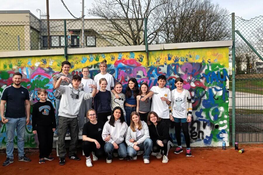 Jugendliche stehen vor einer Grafitti-Wand