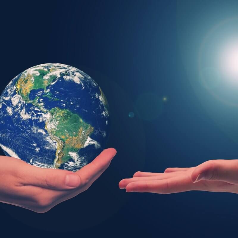 Eine Hand hält die Erdkugel, eine zweite nimmt diese entgegen