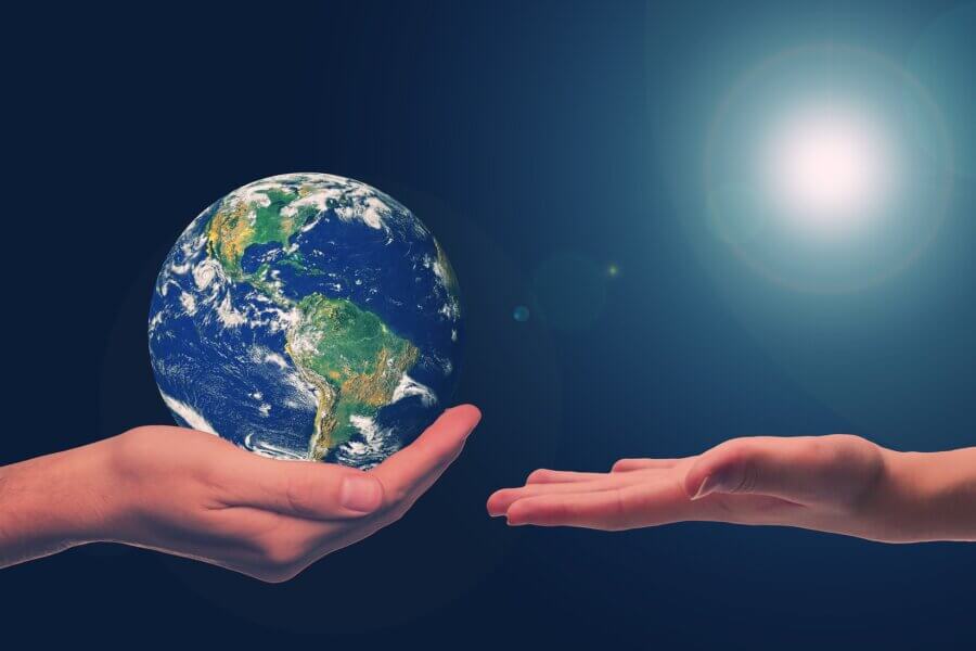 Eine Hand hält die Erdkugel, eine zweite nimmt diese entgegen