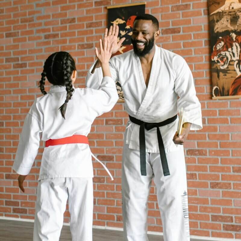 Ein Mann und ein Mädchen im Karate-Anzug klatschen sich ab