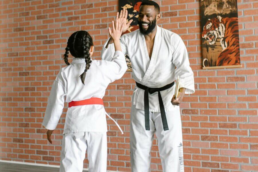 Ein Mann und ein Mädchen im Karate-Anzug klatschen sich ab